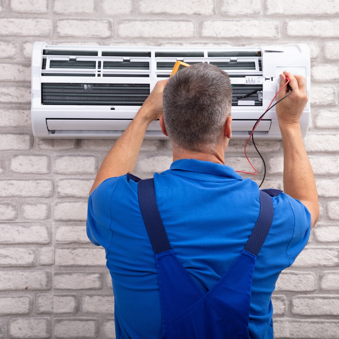 A HVAC professional working on an AC wall unit