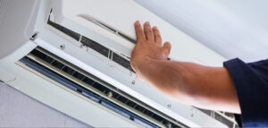 Person inspecting or adjusting a wall-mounted heating unit.