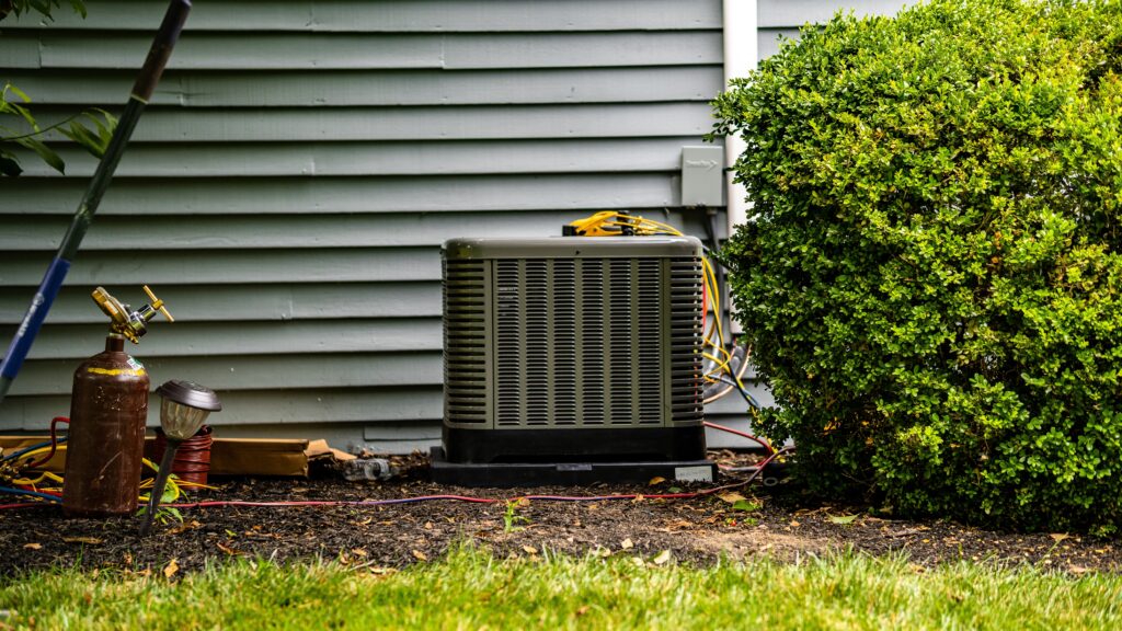 HVAC repairs come in all shapes and sizes. Recognizing the signs can save you a lot of money. this hvac unit on the side of a house next to bushes.