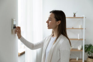 woman looking at heater thermostat