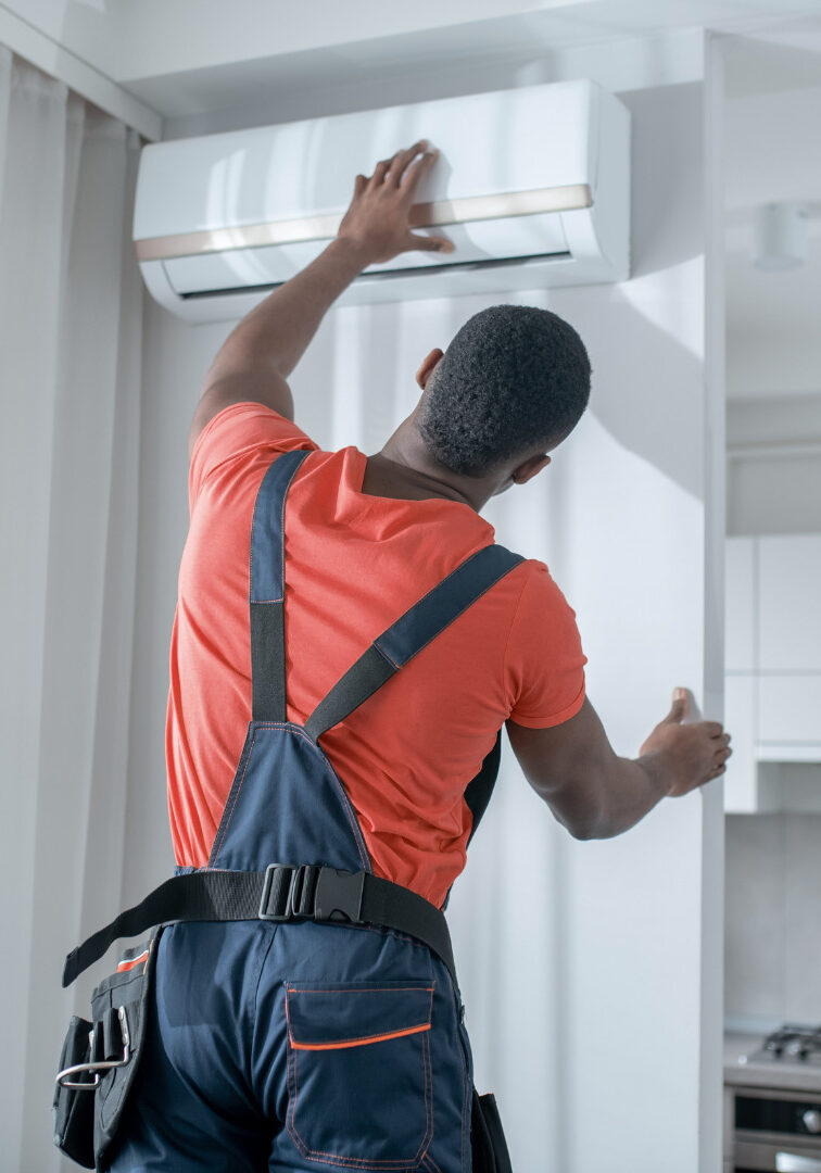 An HVAC professional working on a wall AC unit