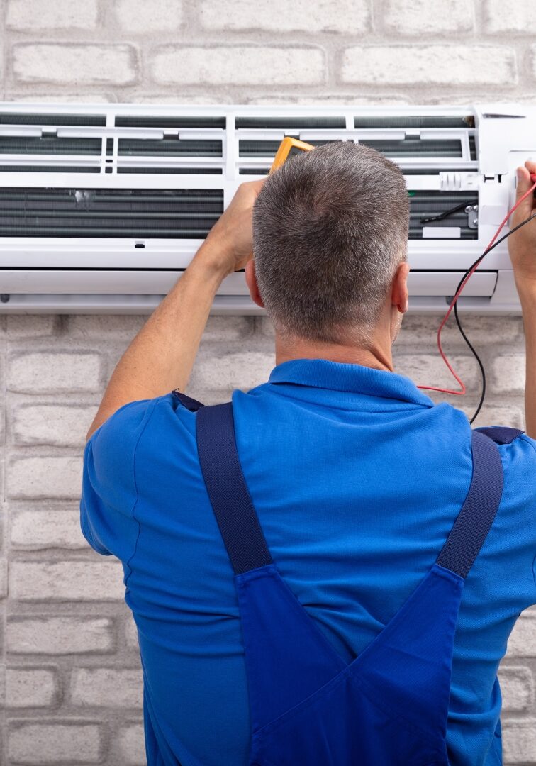 A HVAC professional working on an AC wall unit