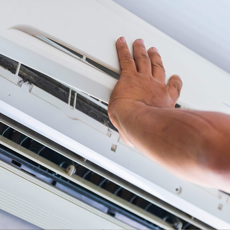 Person inspecting or adjusting a wall-mounted heating unit.